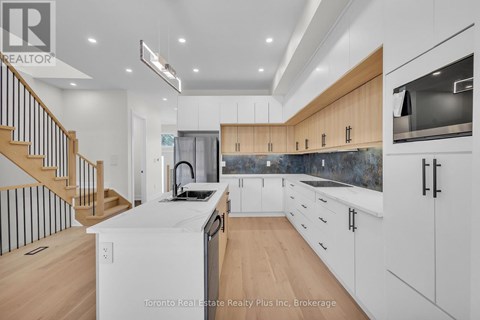 A modern kitchen with wooden cabinets and a staircase.