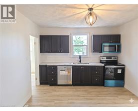 A kitchen with black cabinets and a wooden floor.