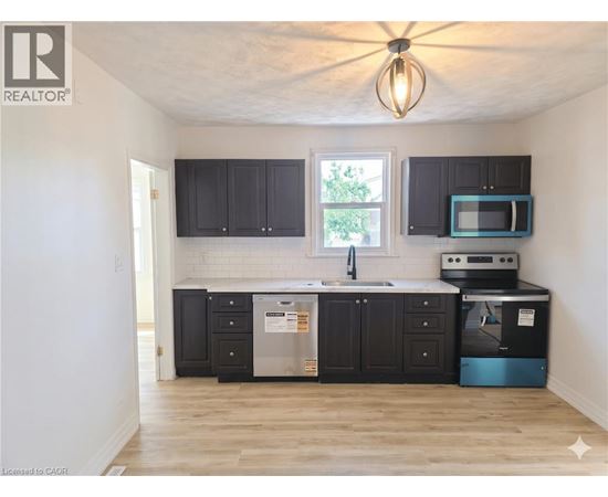 A kitchen with black cabinets and a wooden floor.