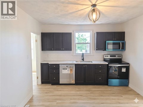 A kitchen with black cabinets and a wooden floor.