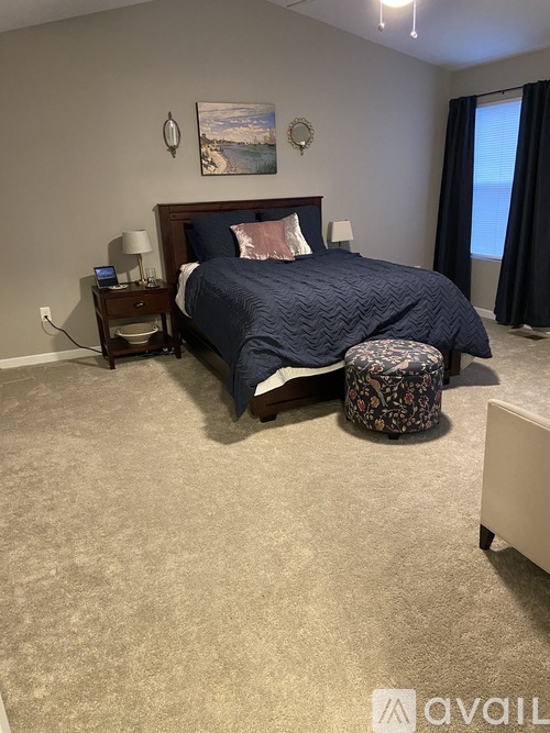 A bedroom with a bed, nightstand, and chair.