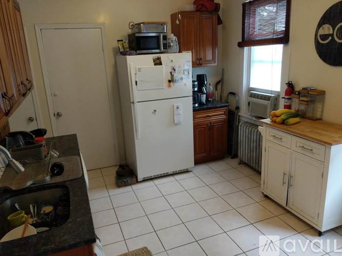 A kitchen with a white fridge, black countertops, and wooden cabinets.