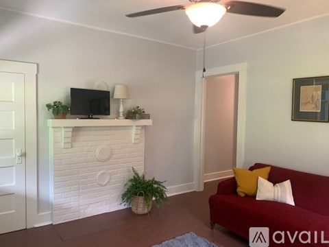 A living room with a red couch and a white brick fireplace.