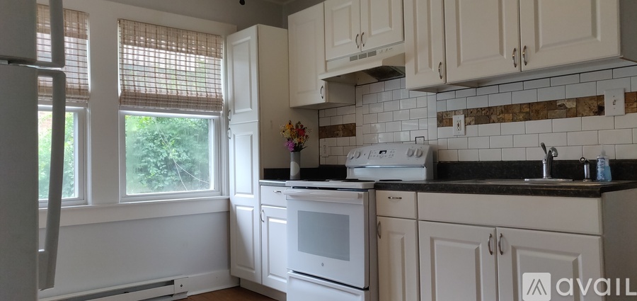 A kitchen with white cabinets and a black countertop.
