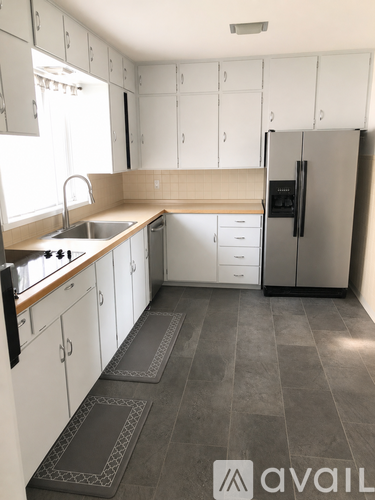 A kitchen with white cabinets and a grey fridge.
