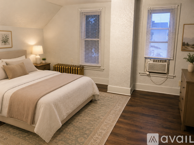 A bedroom with a large bed and a window with blinds.