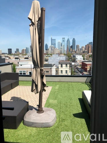 A patio with a table, chairs and a large umbrella overlooking a city skyline.