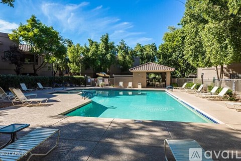 A pool area with sun loungers and a gazebo.