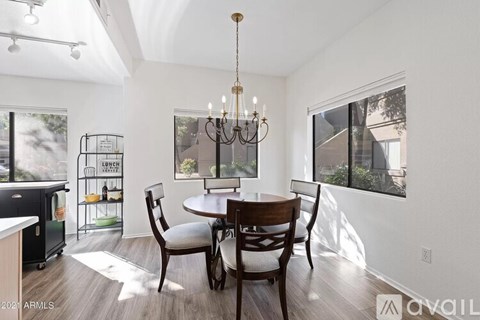A dining room with a table set for four and a chandelier hanging from the ceiling.