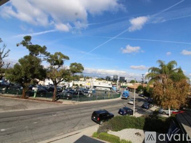 A parking lot with cars and trees under a blue sky.
