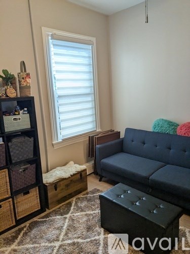 A living room with a dark blue couch, a wooden cabinet with baskets, and a rug on the floor.