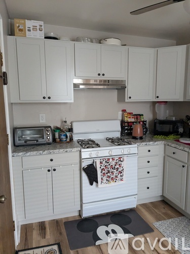 A kitchen with white cabinets and a wooden floor.