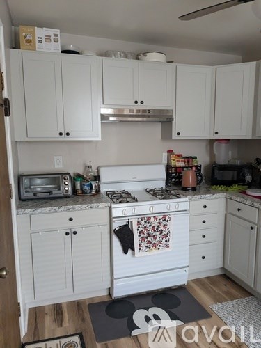 A kitchen with white cabinets and a wooden floor.