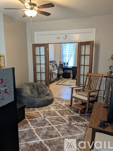 A living room with a rug, a chair, a bean bag, and a ceiling fan.