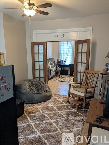 A living room with a rug, a chair, a bean bag, and a ceiling fan.