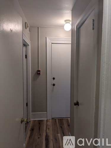 A hallway with a white door and a light on.