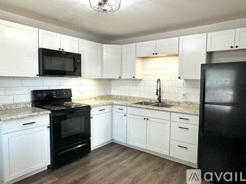 A kitchen with black appliances and white cabinets.