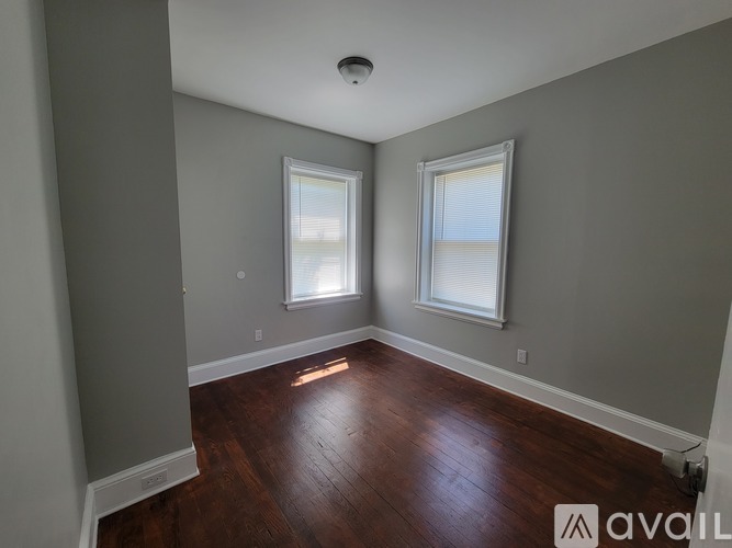 A room with wooden floors and two windows.