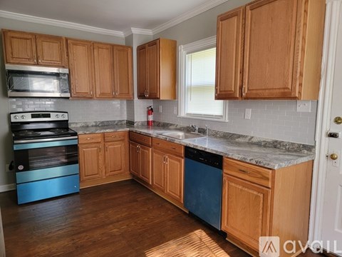A kitchen with wooden cabinets and a blue dishwasher.