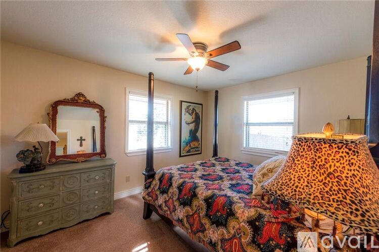 A bedroom with a leopard print bedspread and a ceiling fan.