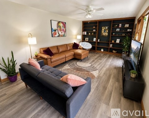 A living room with a brown leather couch and a black sofa.