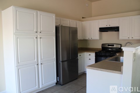 A kitchen with white cabinets and a black fridge.