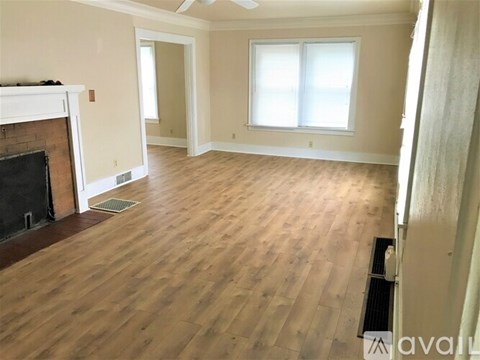 A room with wooden flooring and a fireplace.