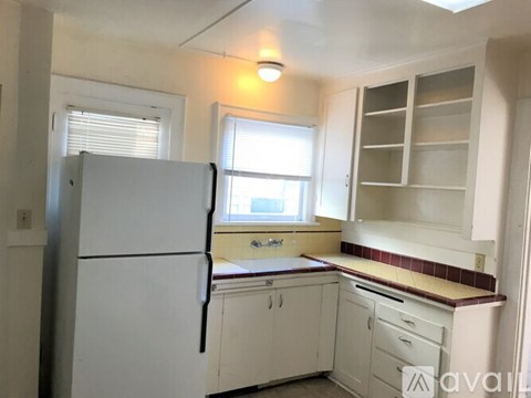 A kitchen with white cabinets and a white refrigerator.