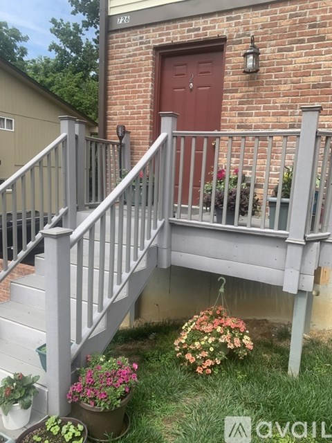 A red door is on a brick building with a grey railing.