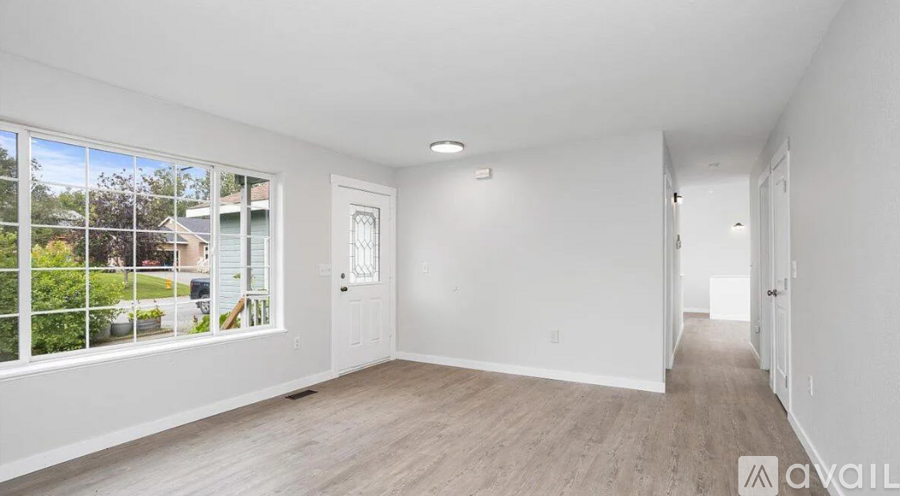 A spacious empty room with a view of a garden through the window.