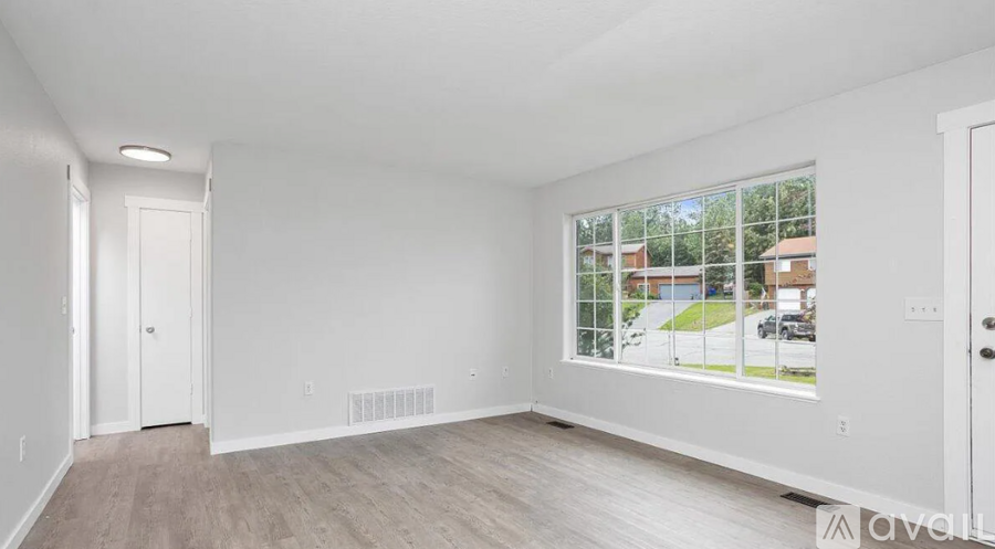 A spacious room with a large window overlooking a residential area.