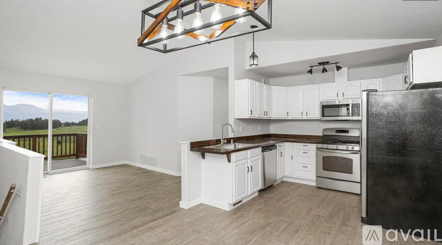 A kitchen with white cabinets and a black refrigerator is available for rent.