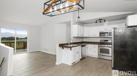 A kitchen with white cabinets and a black refrigerator is available for rent.