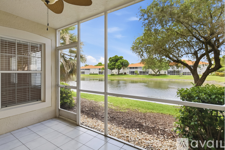 A patio with a sliding glass door leading to a garden with a pond and trees.