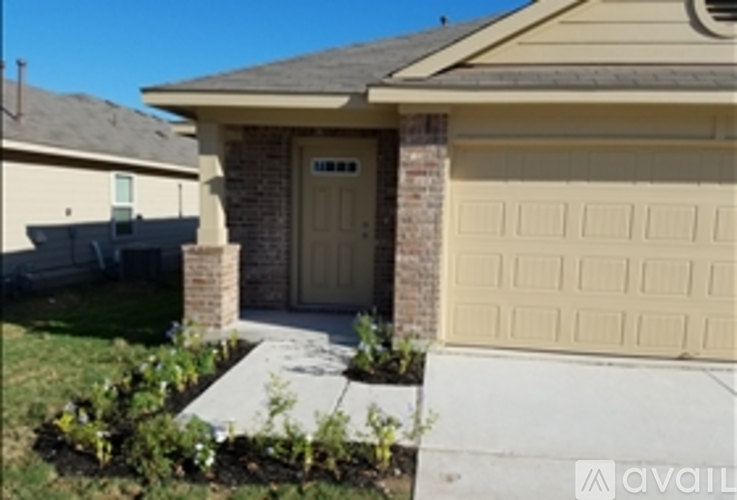 A house with a tan garage door and a brick pillar.