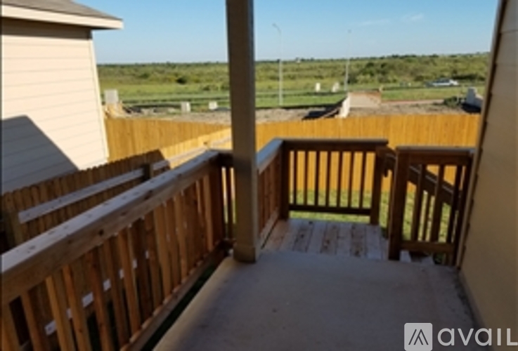 A wooden deck with a view of a grassy field.