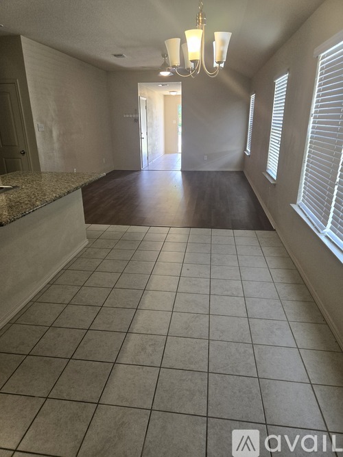 A spacious room with a tiled floor and a chandelier.