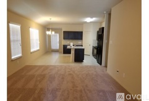A living room with a television and a kitchen area in the background.