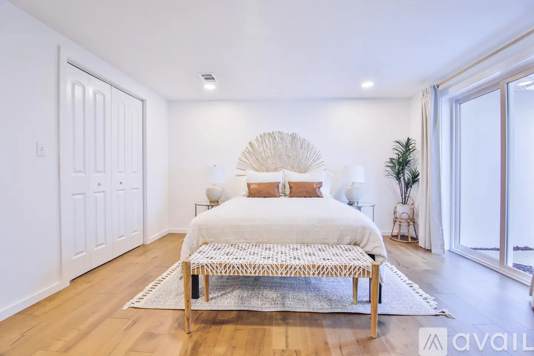 A bedroom with a white bed and a wooden floor.