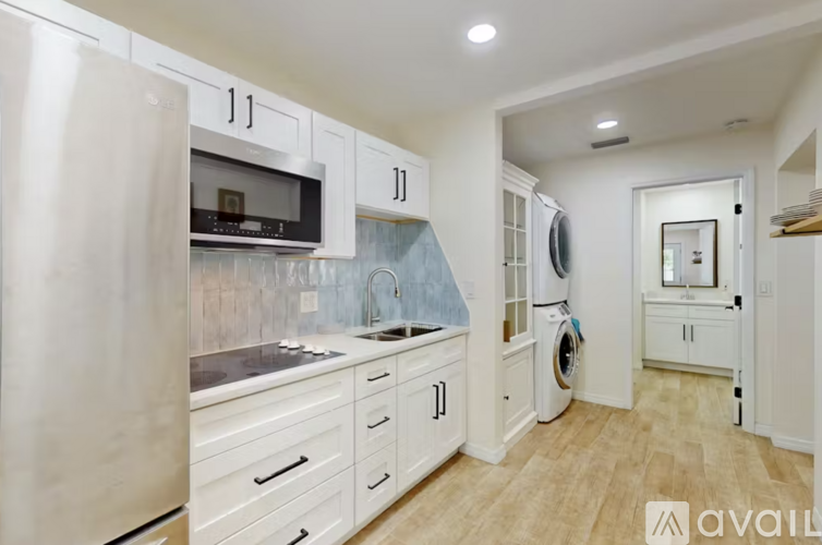 A kitchen with white cabinets and a stainless steel refrigerator.