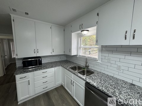 A kitchen with white cabinets and a granite countertop.