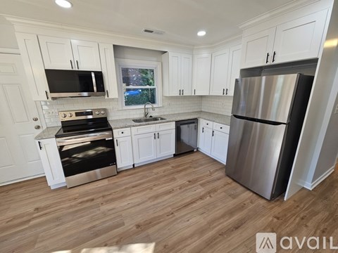 A kitchen with white cabinets and a wooden floor.