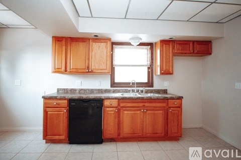 A kitchen with wooden cabinets and a black dishwasher.