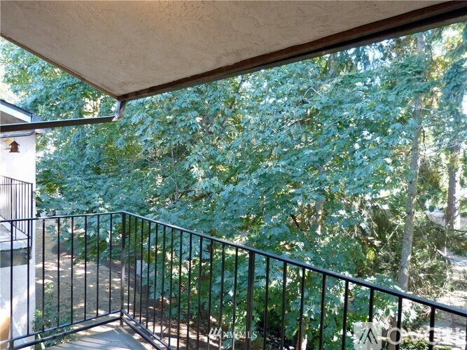 A balcony with a black railing and a view of trees.