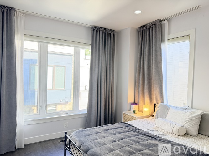 A bedroom with a large bed and a window with curtains.
