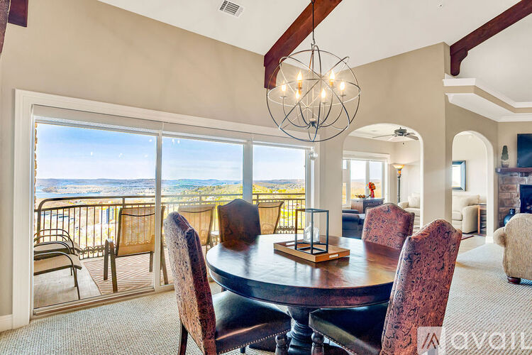 A dining room with a table and chairs and a balcony with a view.