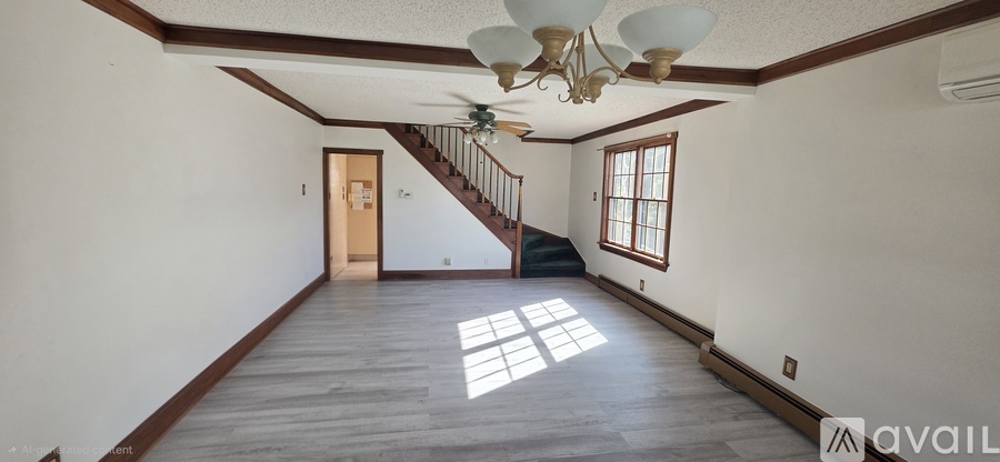 A spacious room with a staircase and a chandelier.