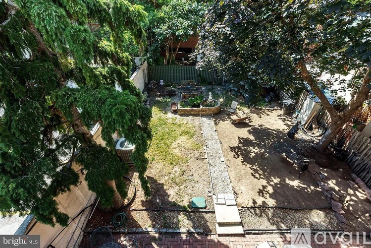 A backyard with a tree, a fence, and a small garden.