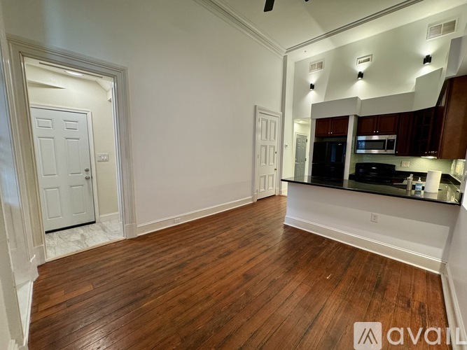 A spacious room with wooden floors and a large mirror on the wall.