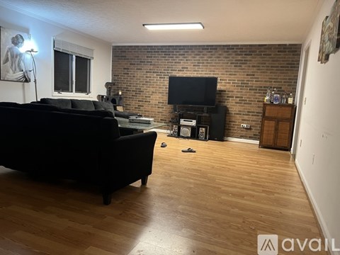A living room with a black couch and a brick wall.